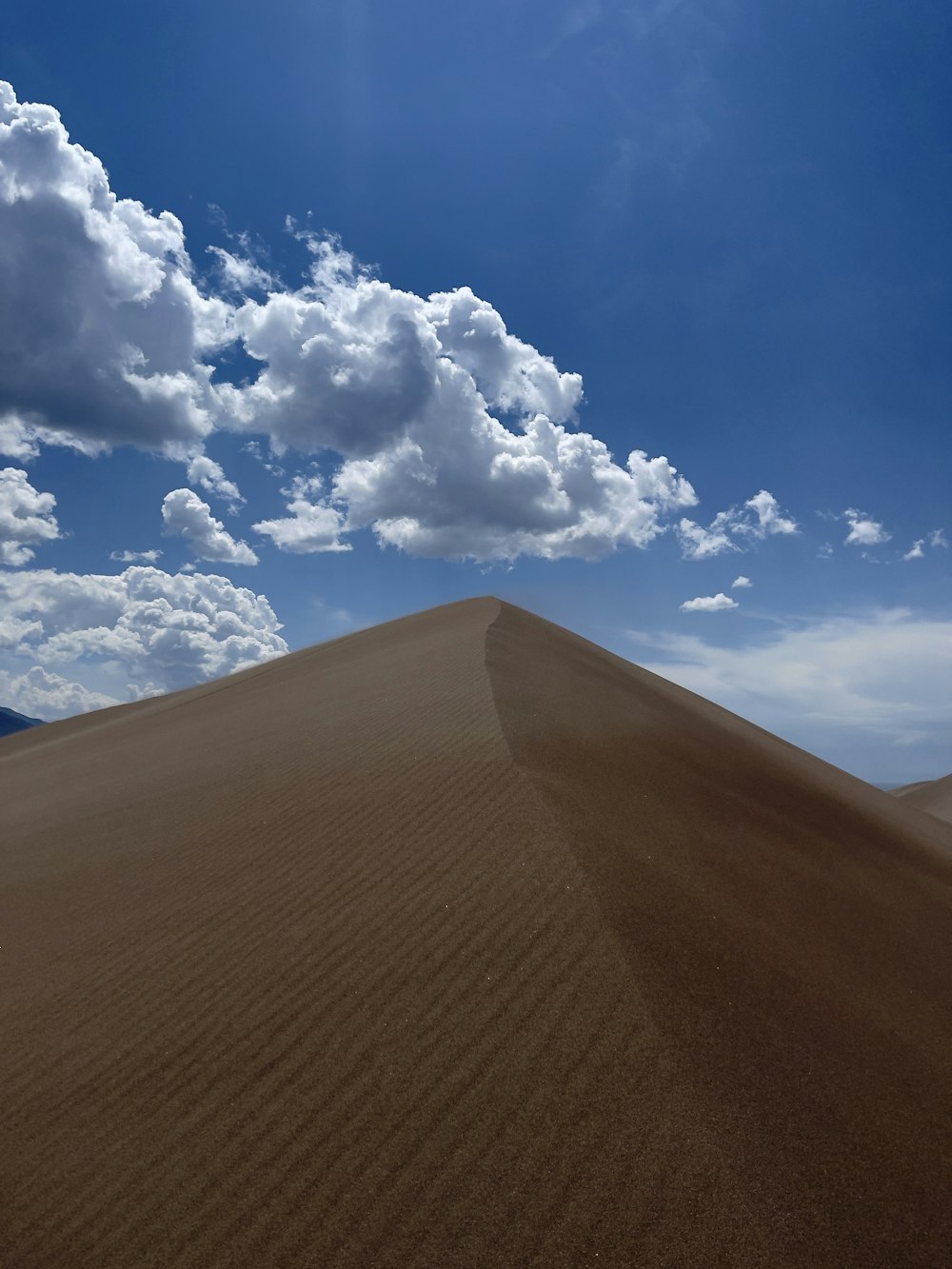 brown sand under blue sky and white clouds during daytime