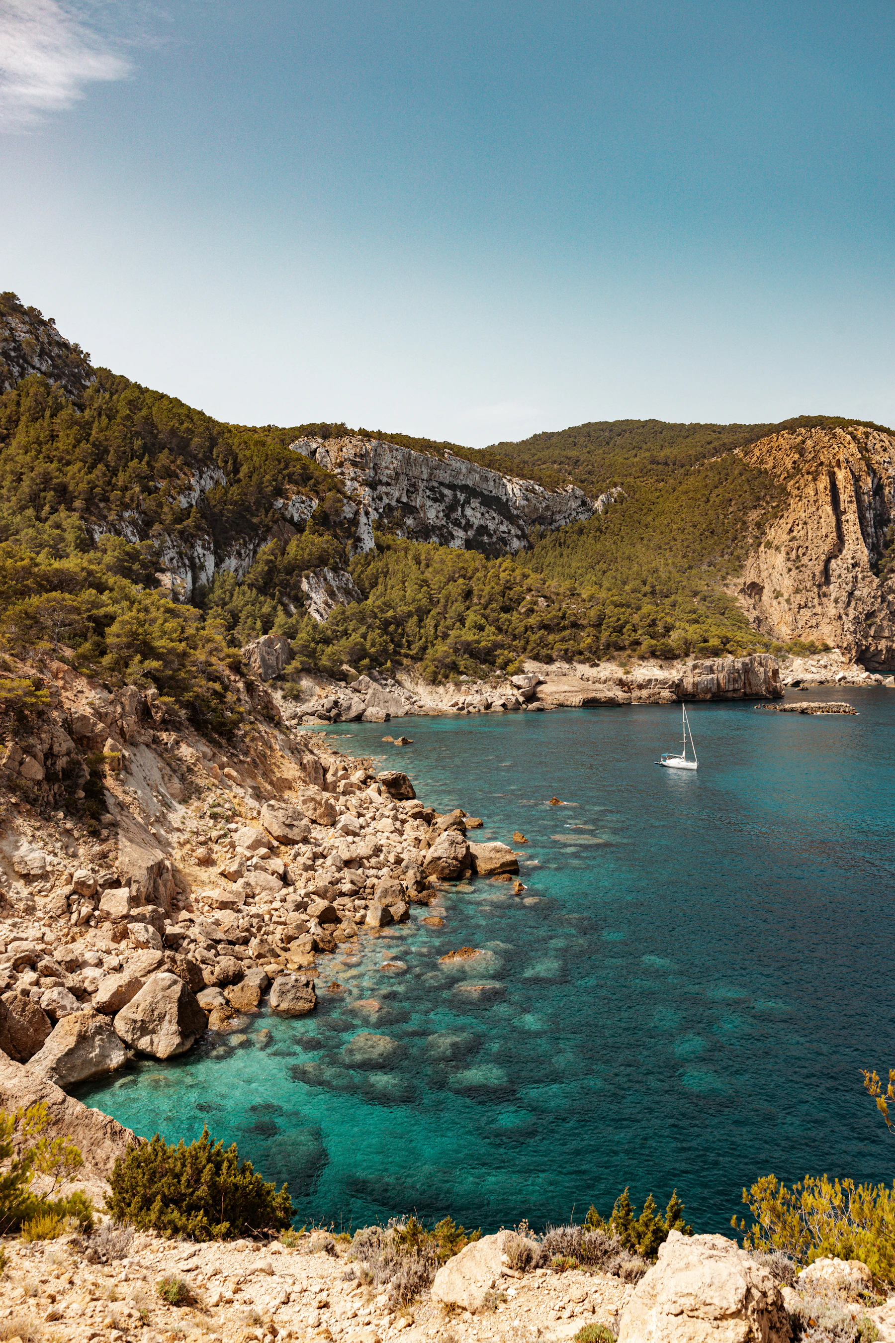 Groene bergen aan het water aan de kust van Ibiza op een heldere dag