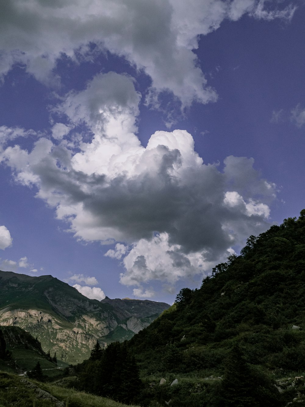 montaña verde bajo nubes blancas y cielo azul durante el día