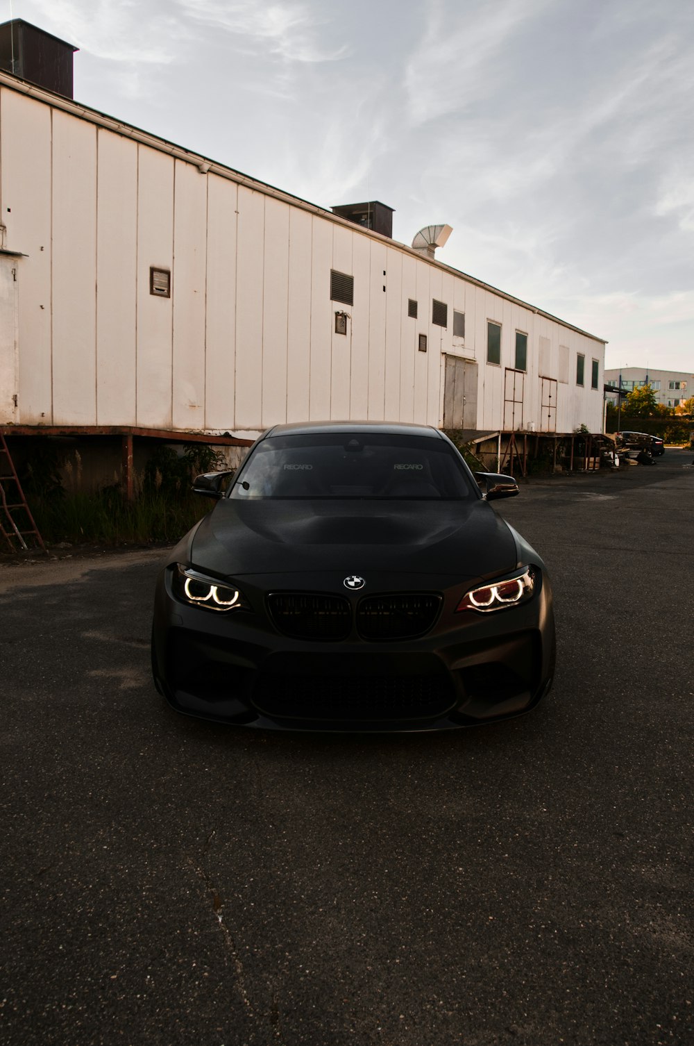 Voiture BMW noire garée près d’un garage blanc pendant la journée