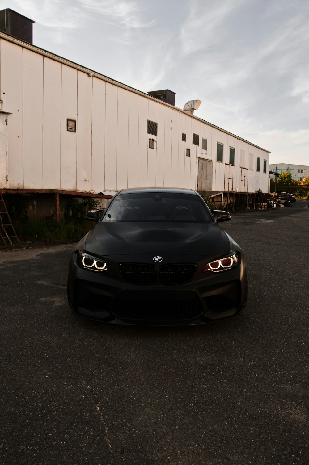 black bmw car parked near white garage during daytime