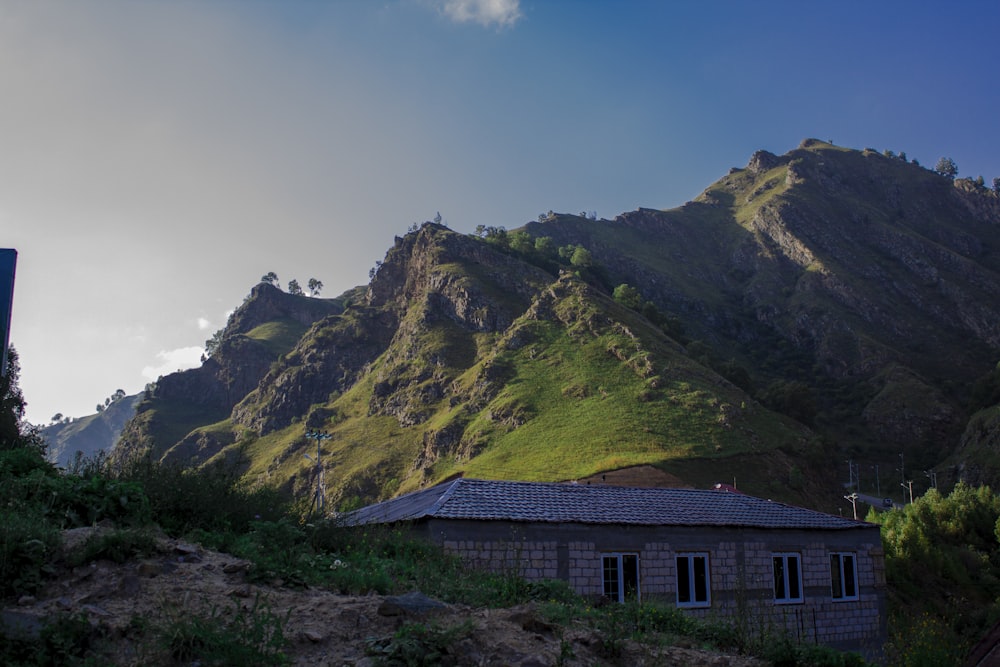 brown and gray house on green mountain under blue sky during daytime