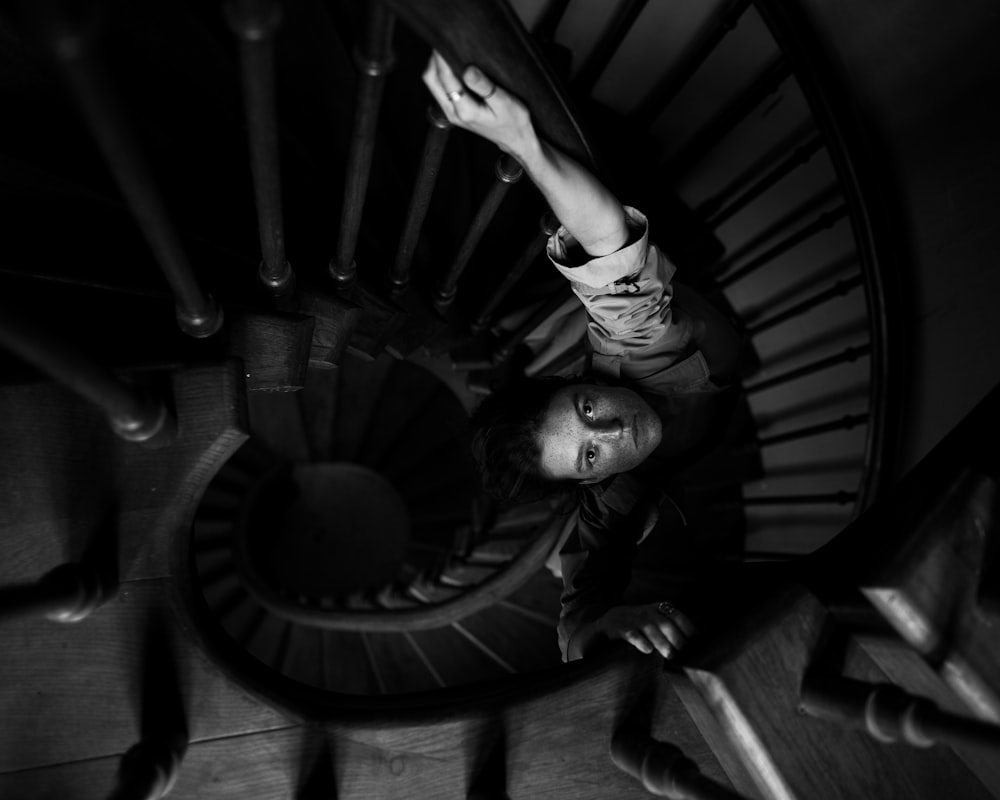 grayscale photo of girl climbing on spiral staircase