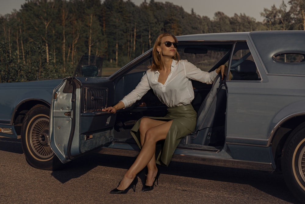 woman in white long sleeve shirt sitting on black car