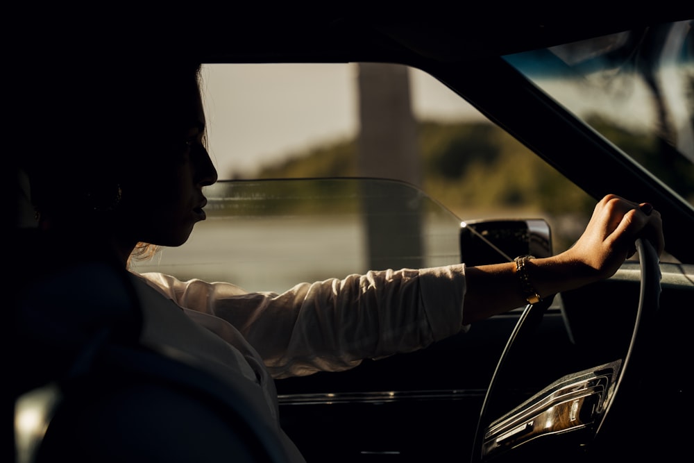 man in white dress shirt driving car during daytime