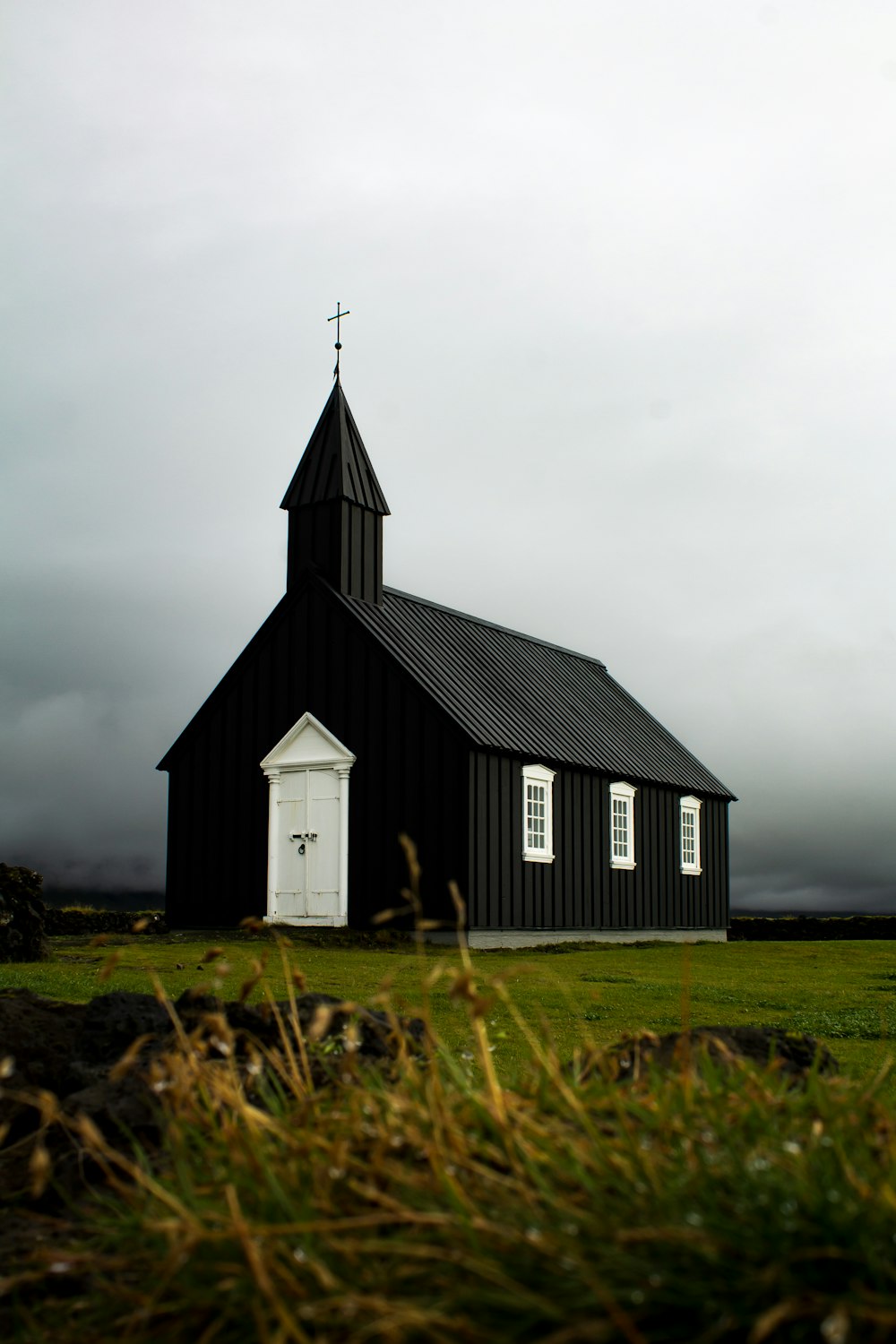 uma igreja preta com uma porta branca e um campanário