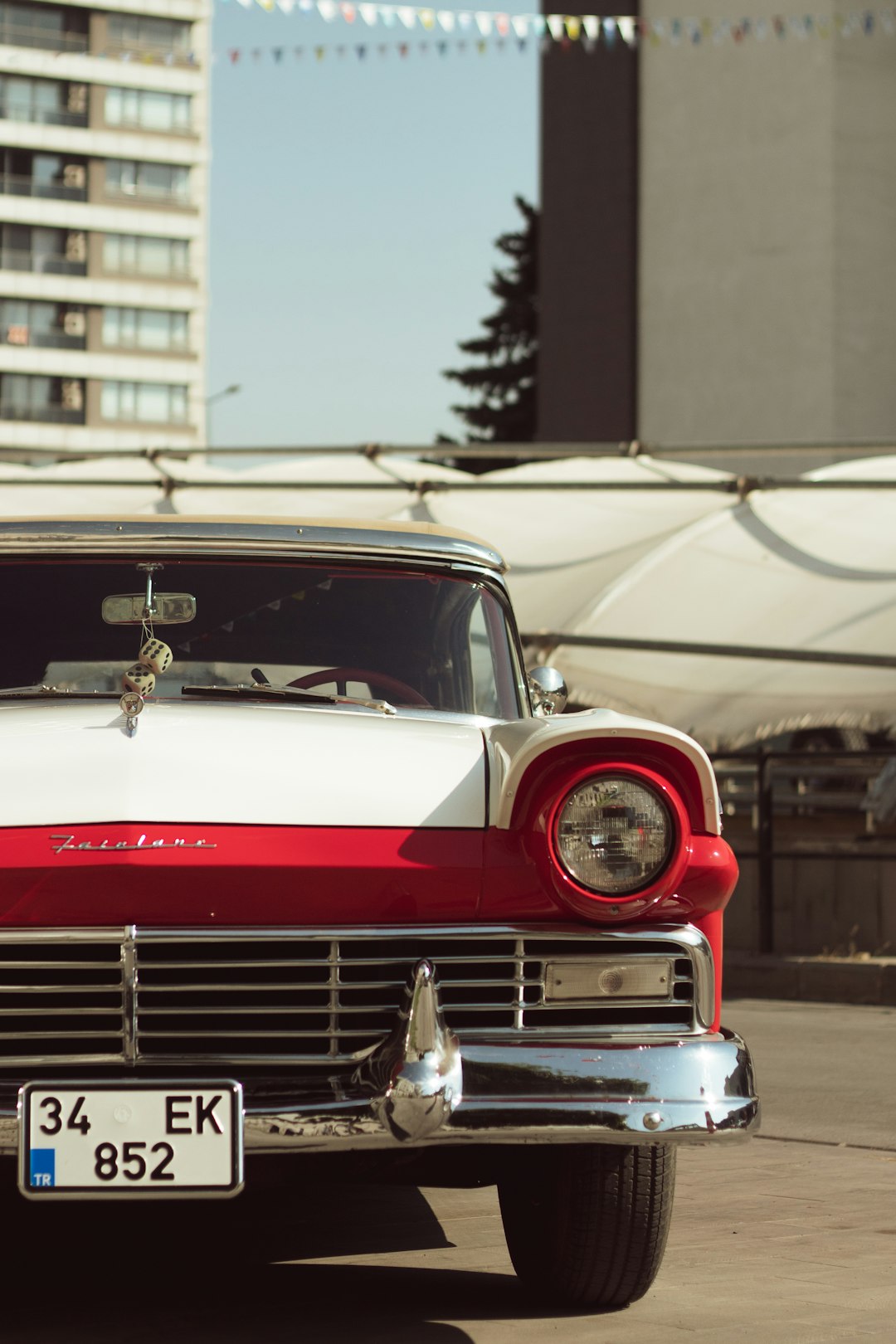 red and silver vintage car in front of white building