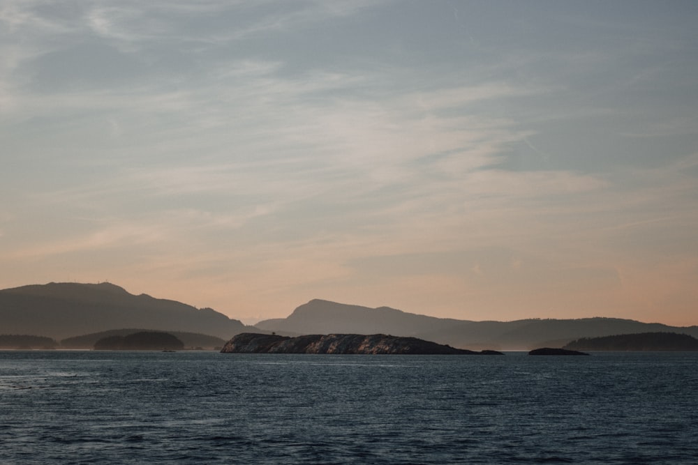 body of water near mountain during daytime