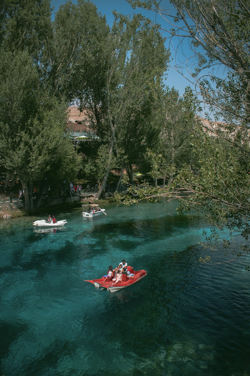 personas que viajan en botes rojos y blancos en el río durante el día