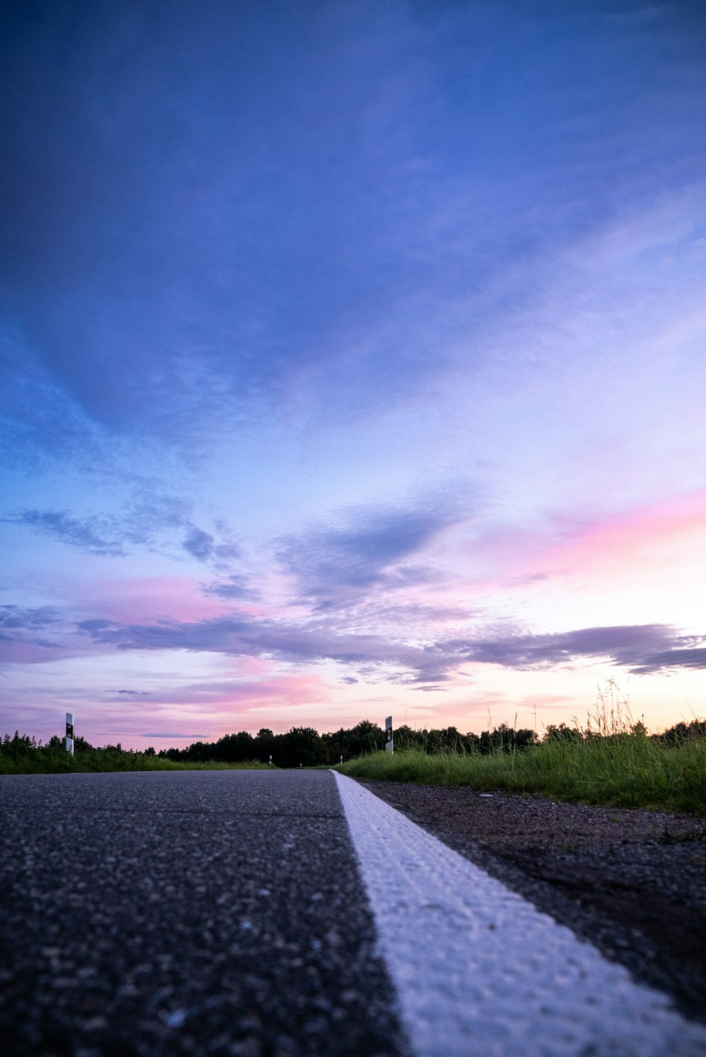 camino de concreto gris entre campo de hierba verde bajo cielo azul durante el día