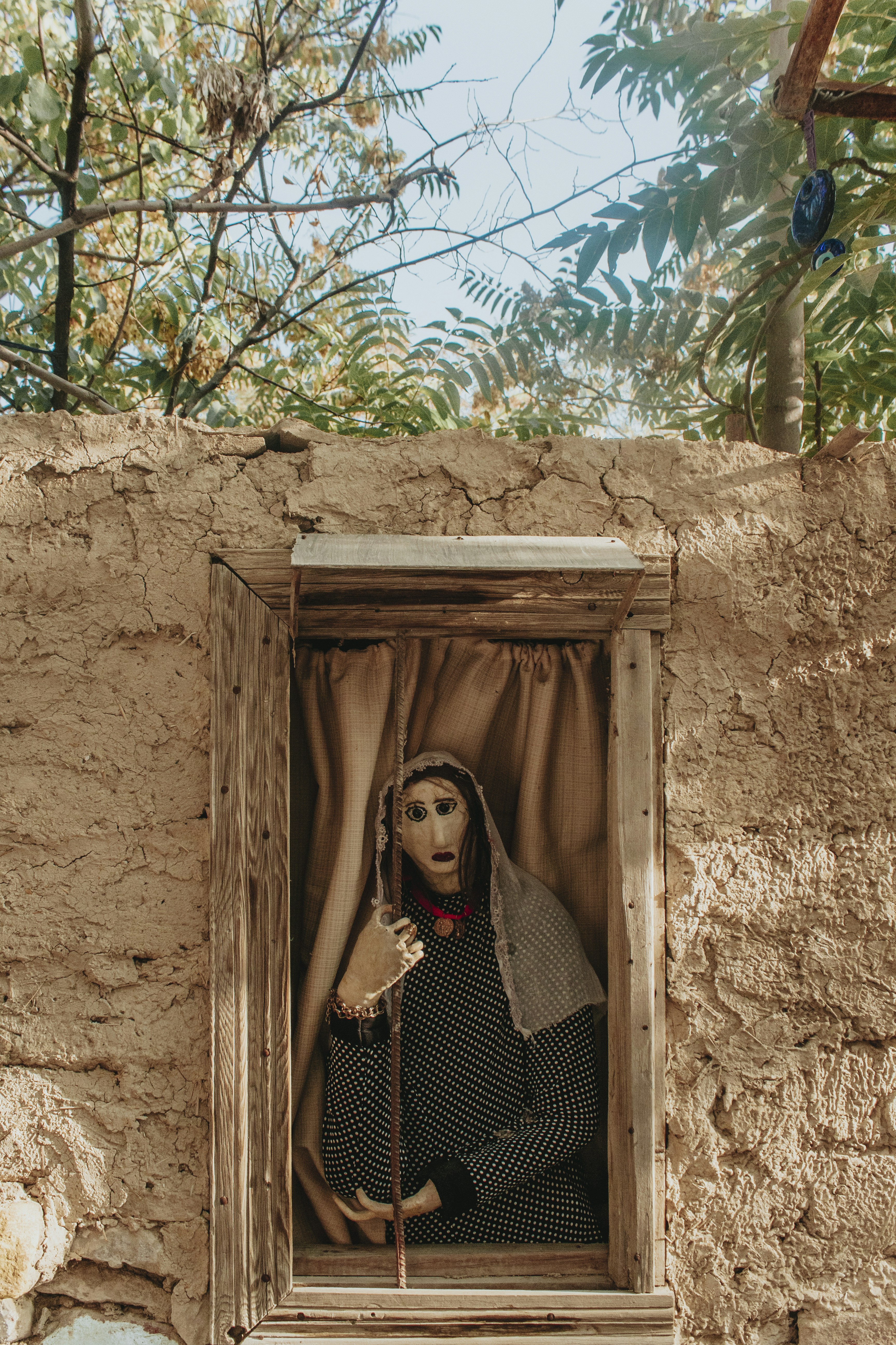 woman in black and white polka dot dress standing near brown wooden door during daytime
