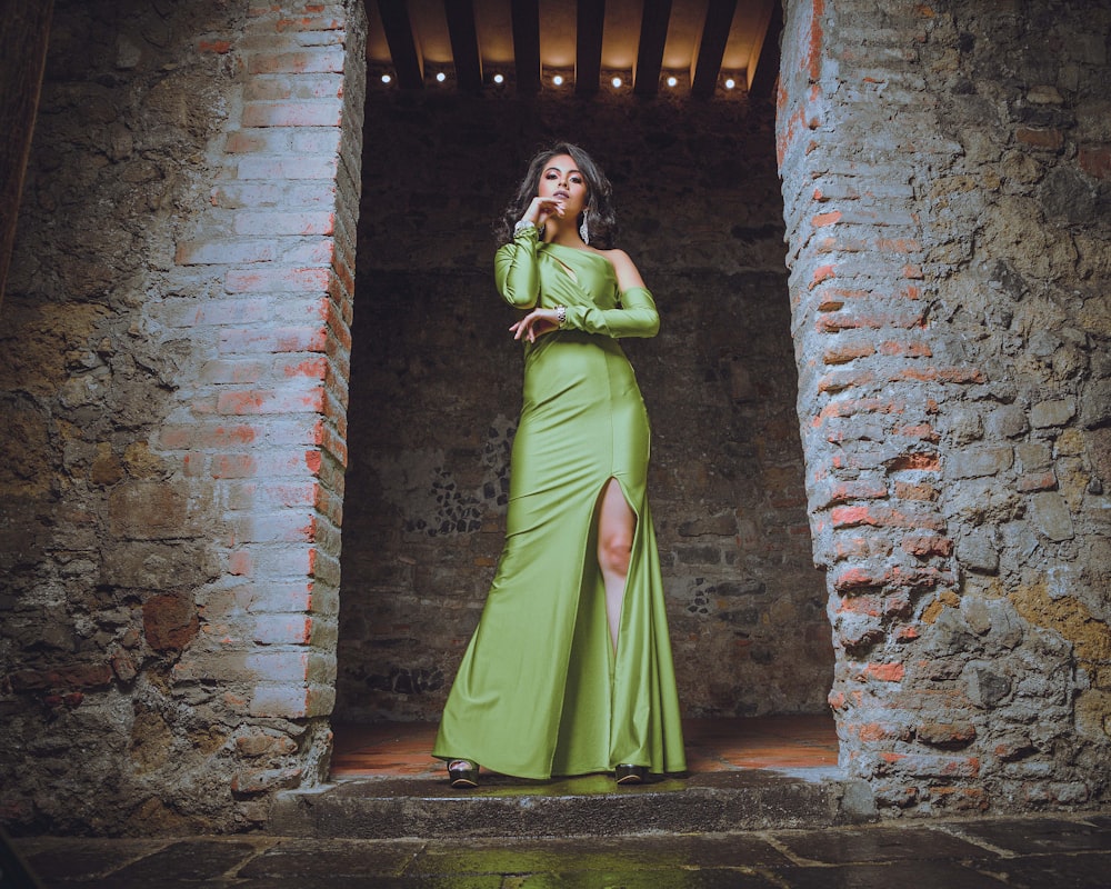 woman in green sari standing beside brown brick wall