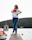 Photo of a confident woman standing on a dock with cargo ships in the background.