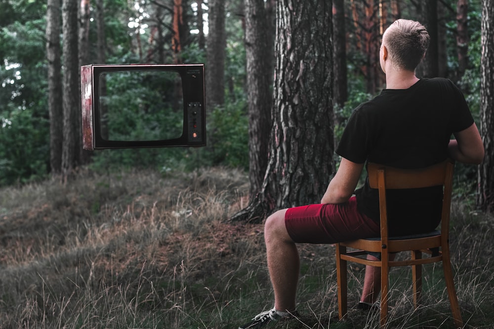 man in black t-shirt sitting on brown wooden chair