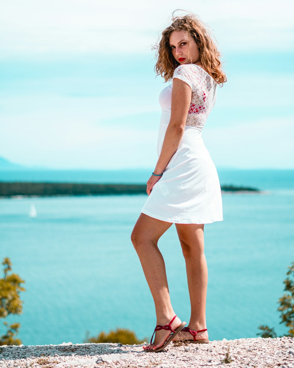 woman in white dress standing on seashore during daytime