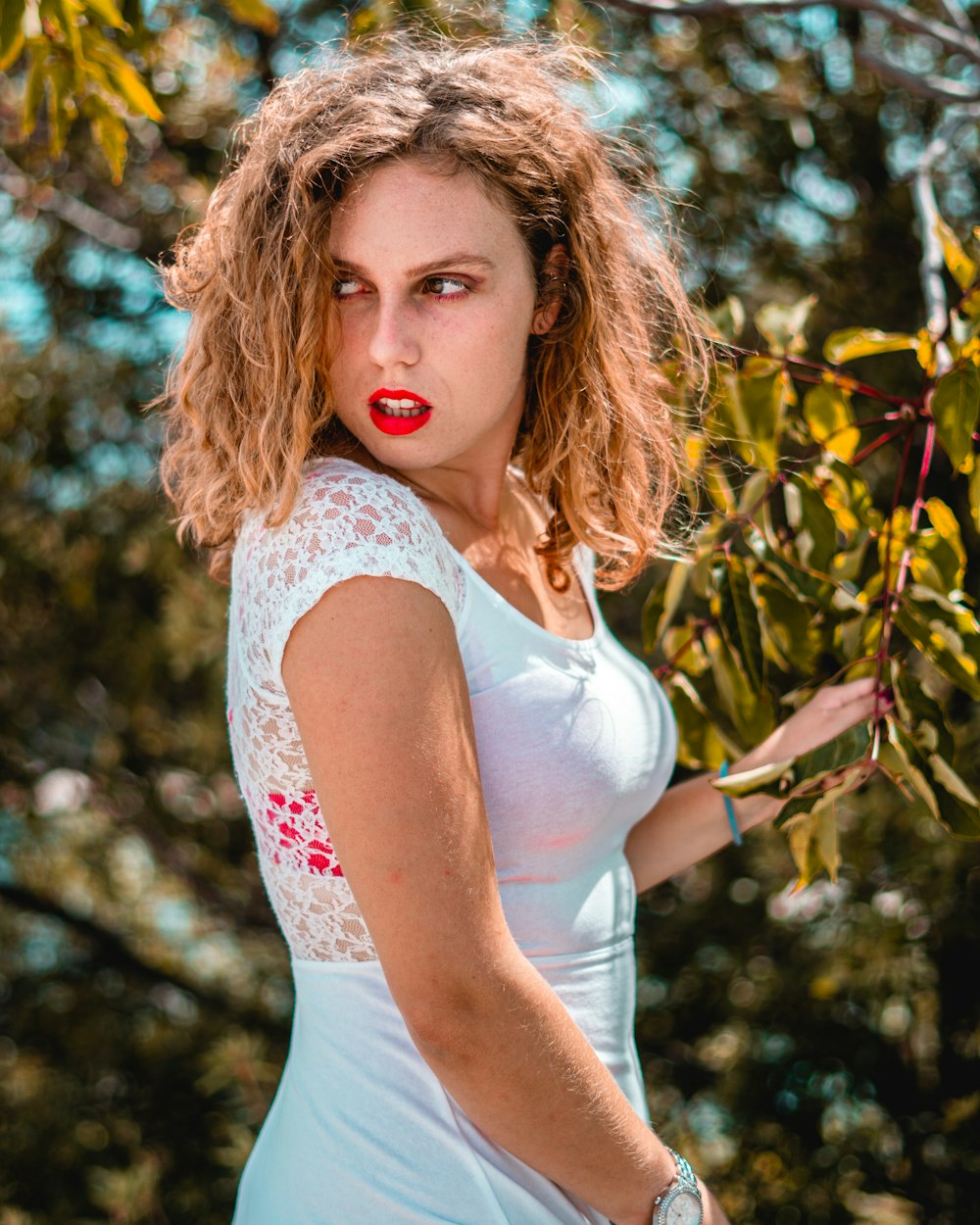 woman in white tank top standing near brown leaf tree during daytime