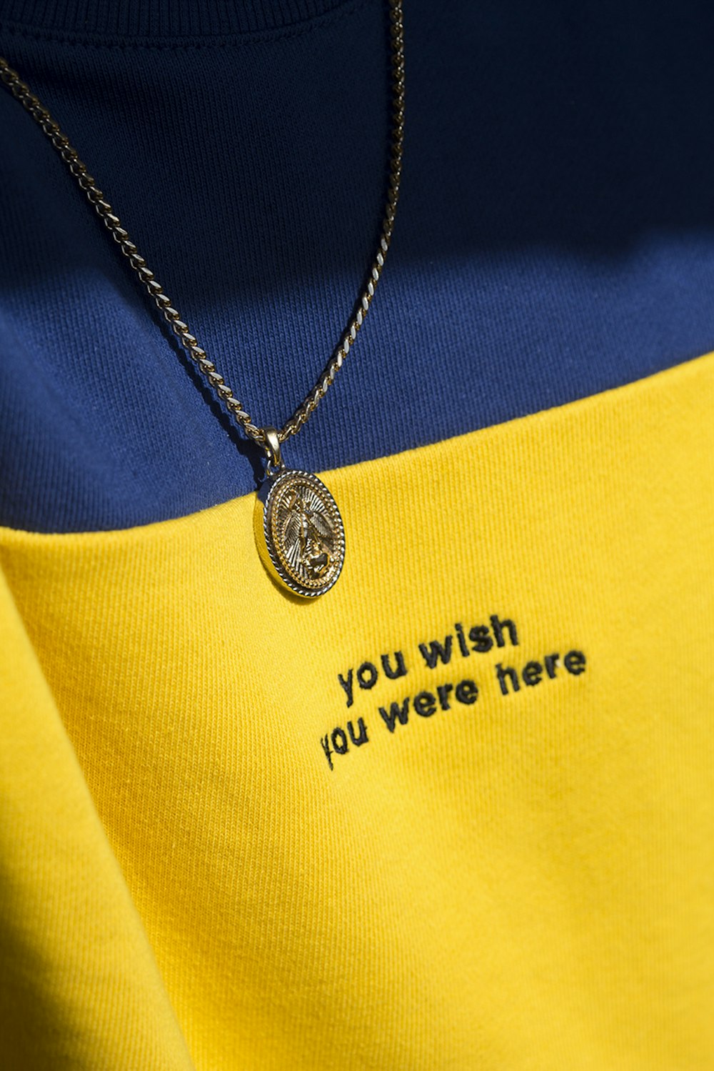 silver round pendant necklace on yellow textile