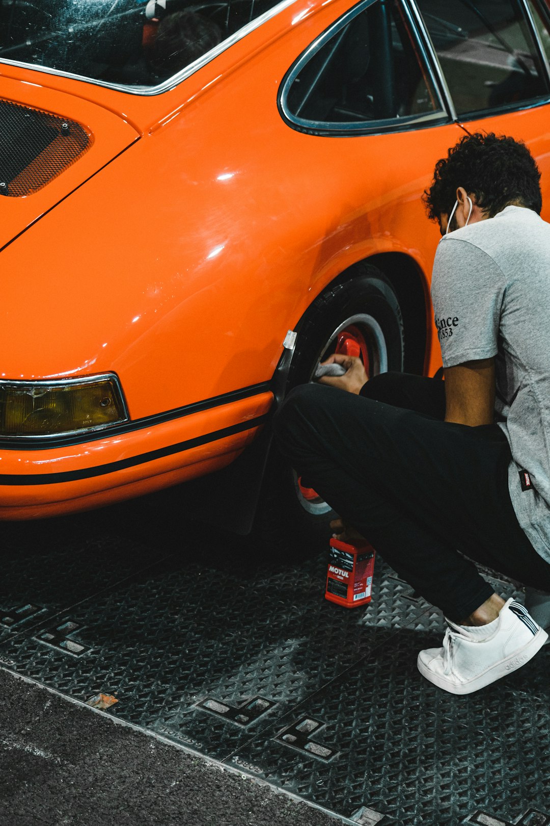 man in gray long sleeve shirt and black pants sitting on orange car