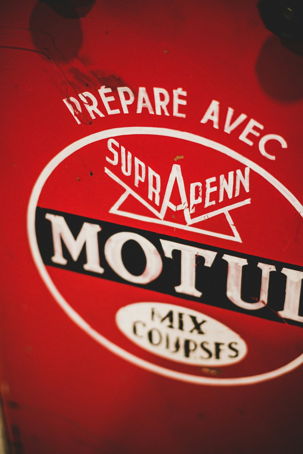 a close up of a motu sign on a red surface