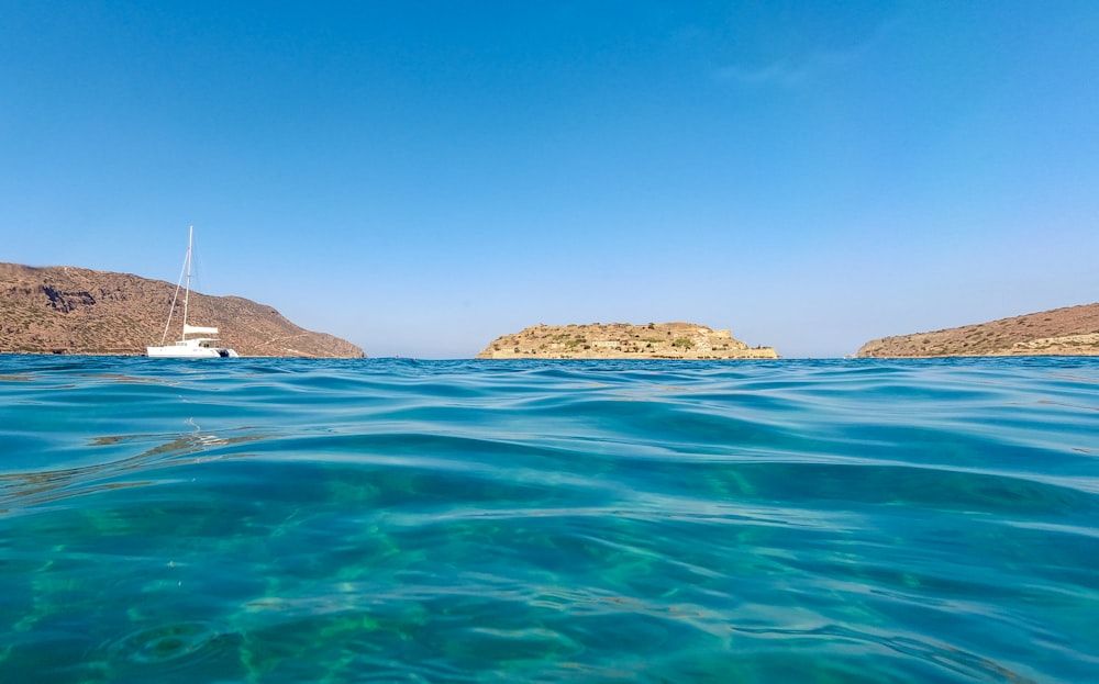 ilha marrom e verde no mar azul sob o céu azul durante o dia