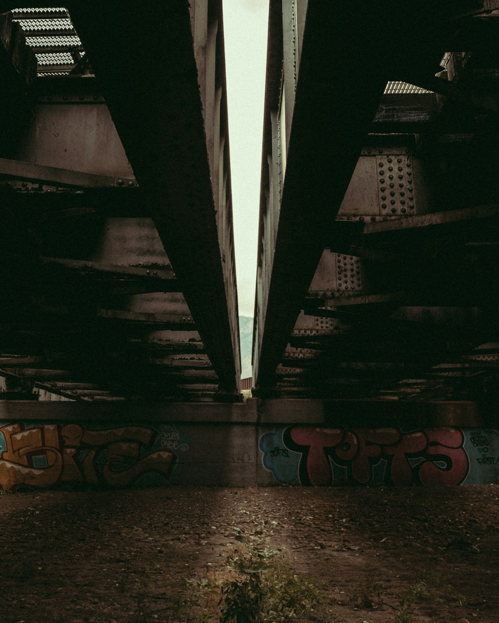 a view of the underside of a bridge with graffiti on it