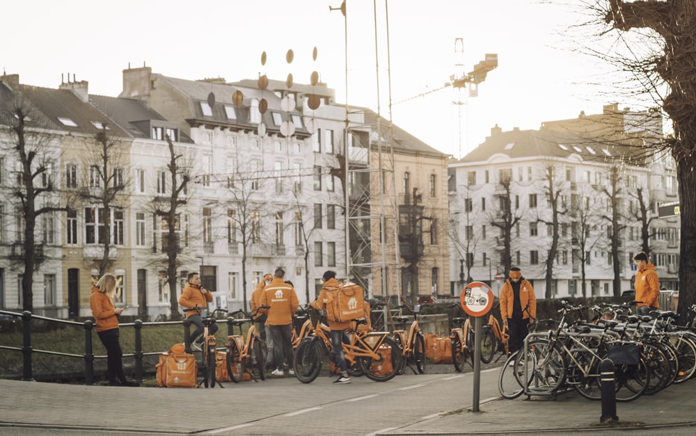 people in orange shirts riding bicycles on road during daytime