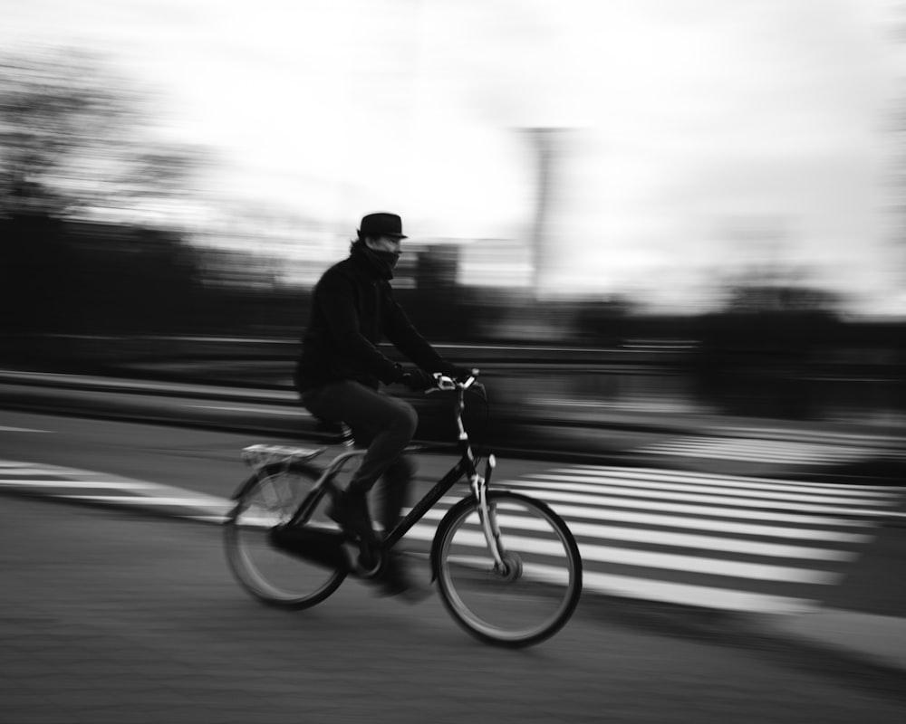 man riding bicycle in grayscale photography