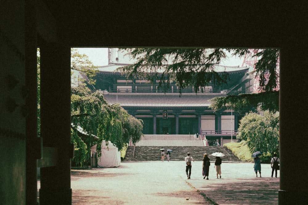 people walking on sidewalk near green trees during daytime