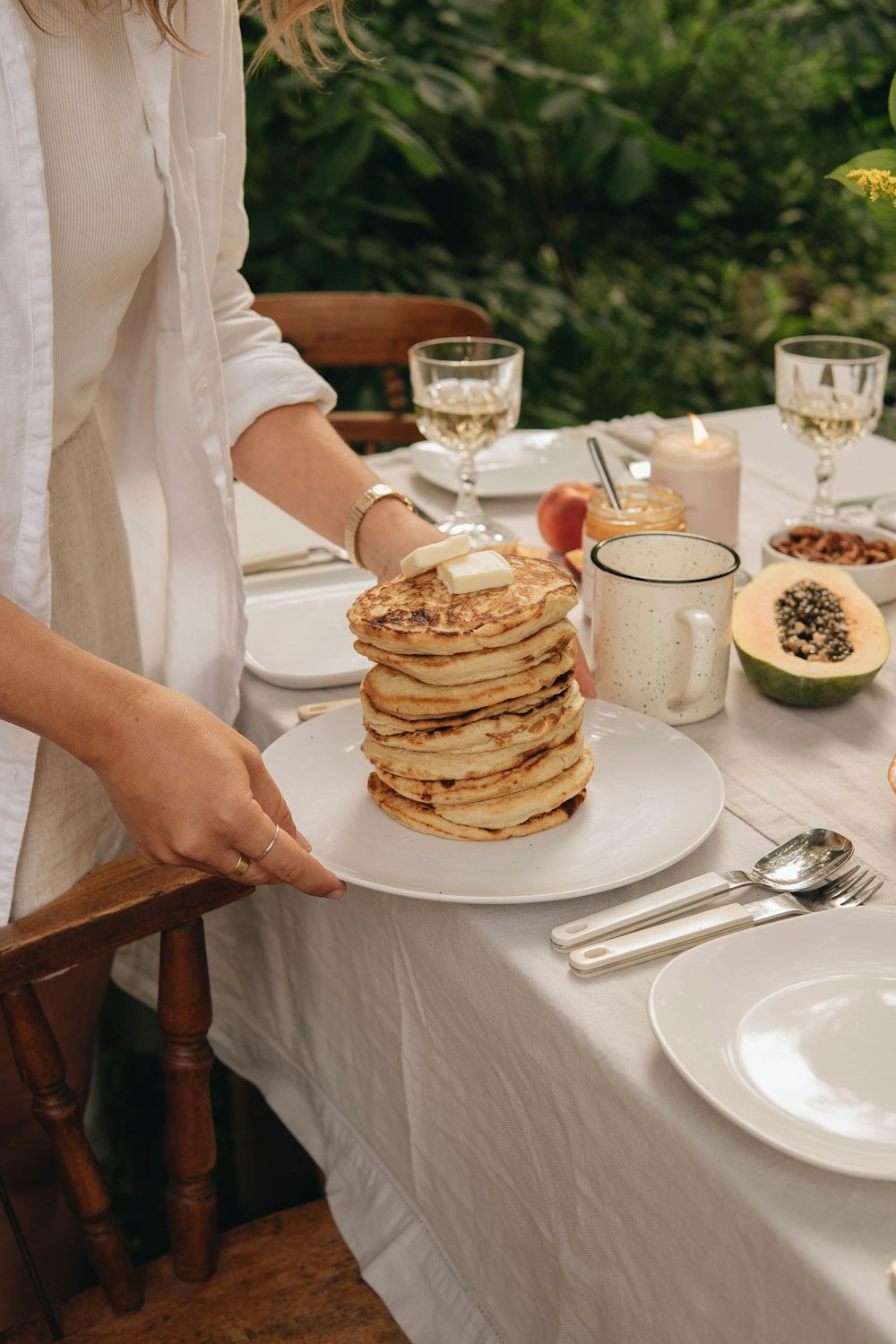 woman in white dress holding white ceramic plate with pancakes