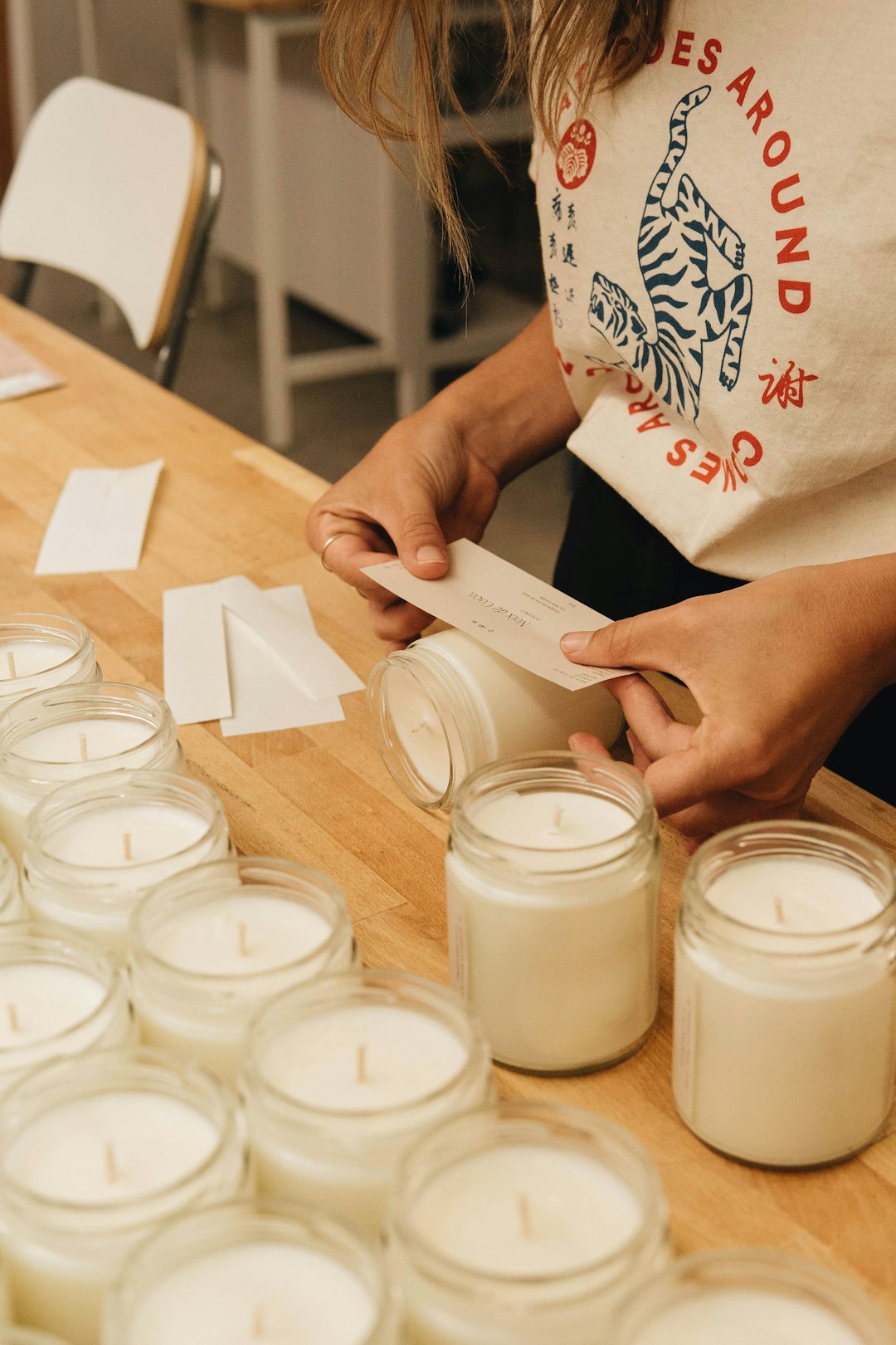 person holding white printer paper near clear glass jars