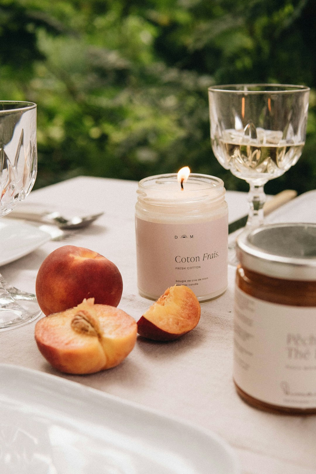 white pillar candle beside clear wine glass on white table