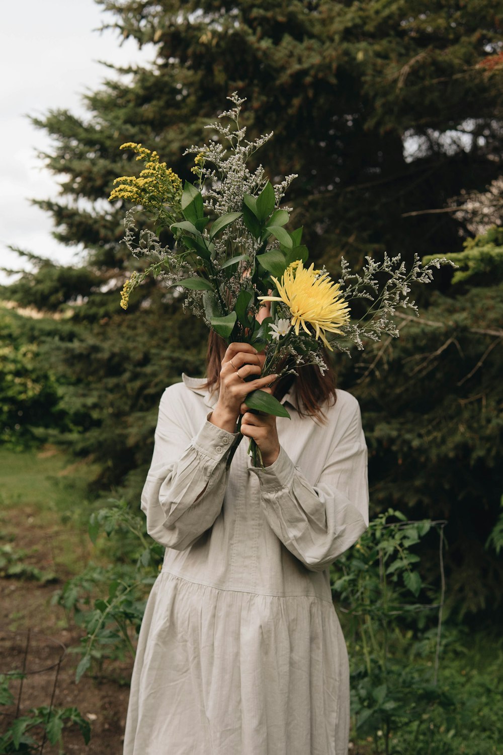 woman in white dress holding sunflower