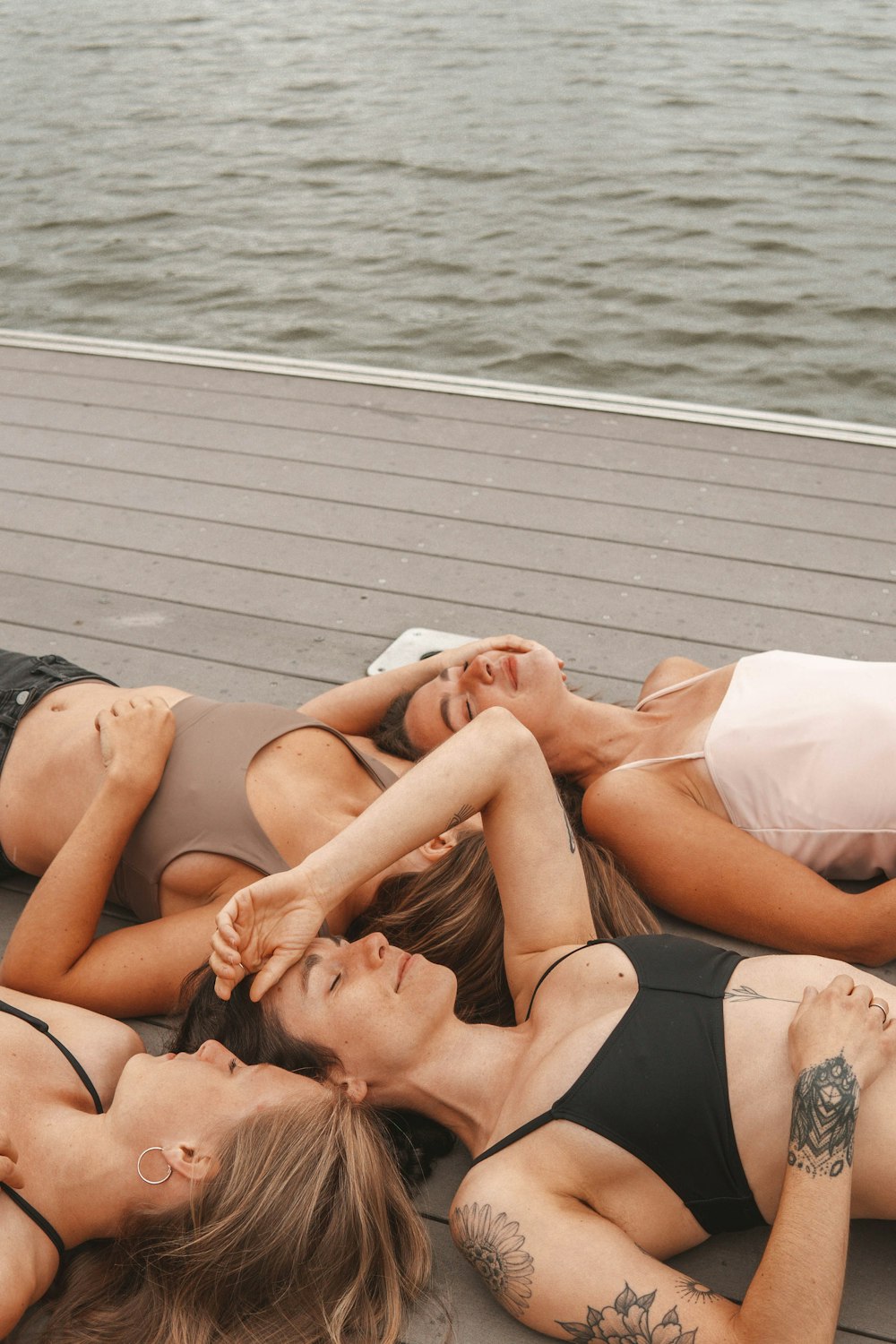 2 women lying on gray wooden dock during daytime