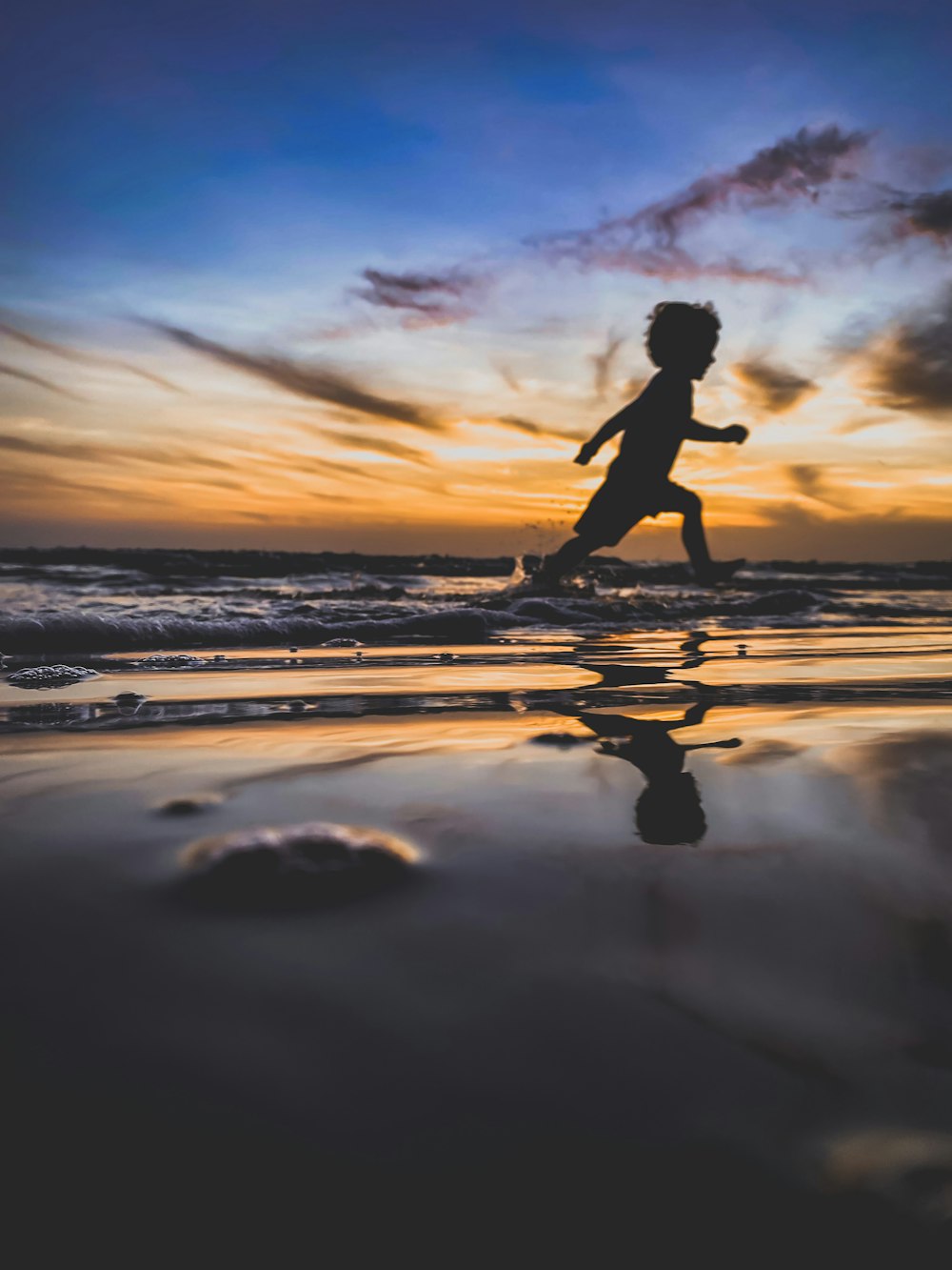 夕暮れ時の浜辺を走る女性のシルエット