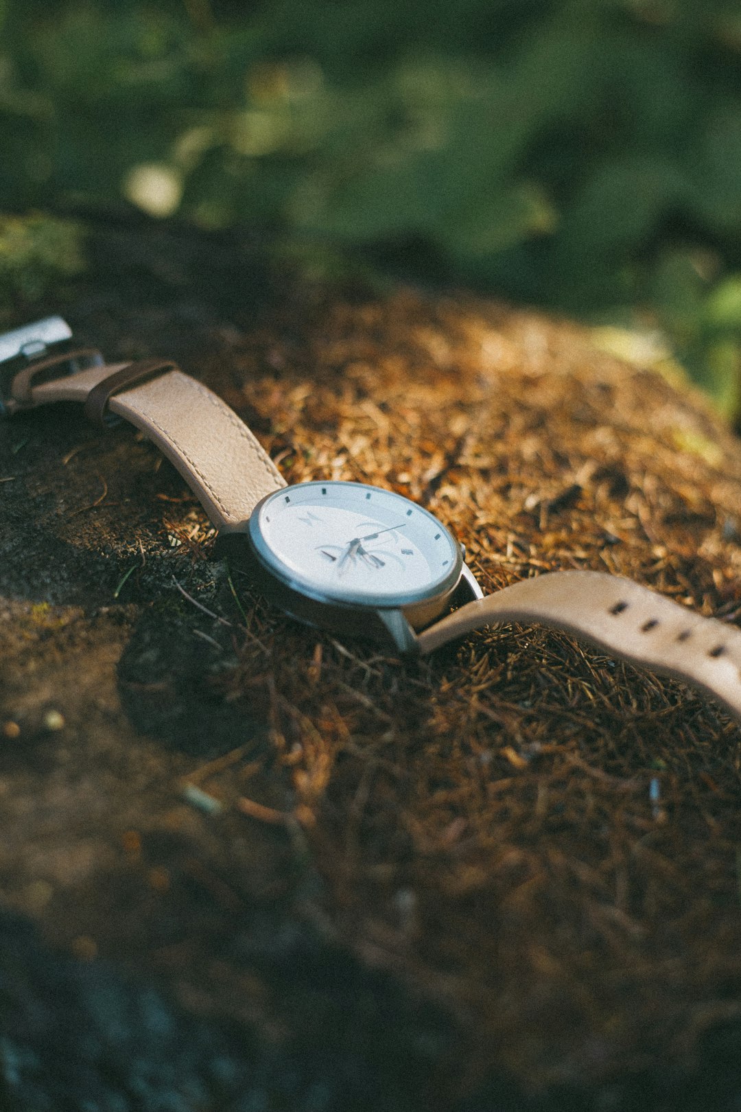 silver round analog watch with white leather strap