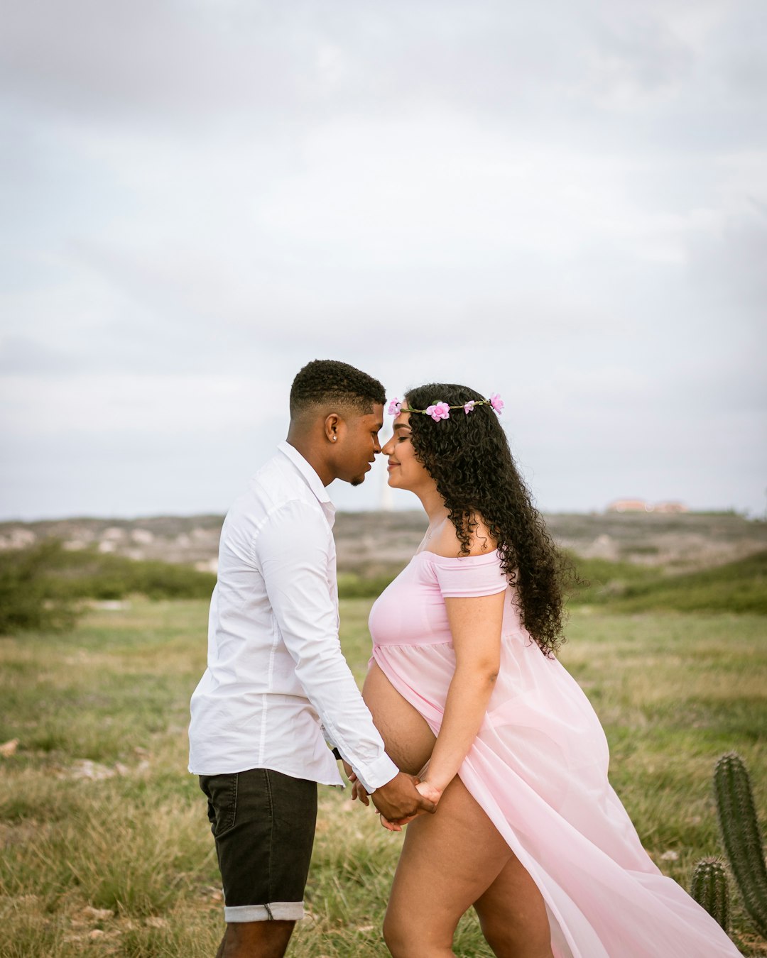 man in white dress shirt kissing woman in white dress on green grass field during daytime