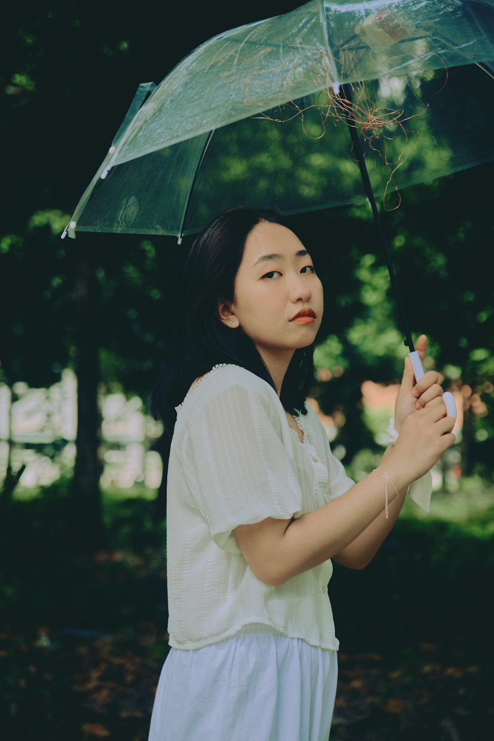 donna in camicia bianca che tiene l'ombrello