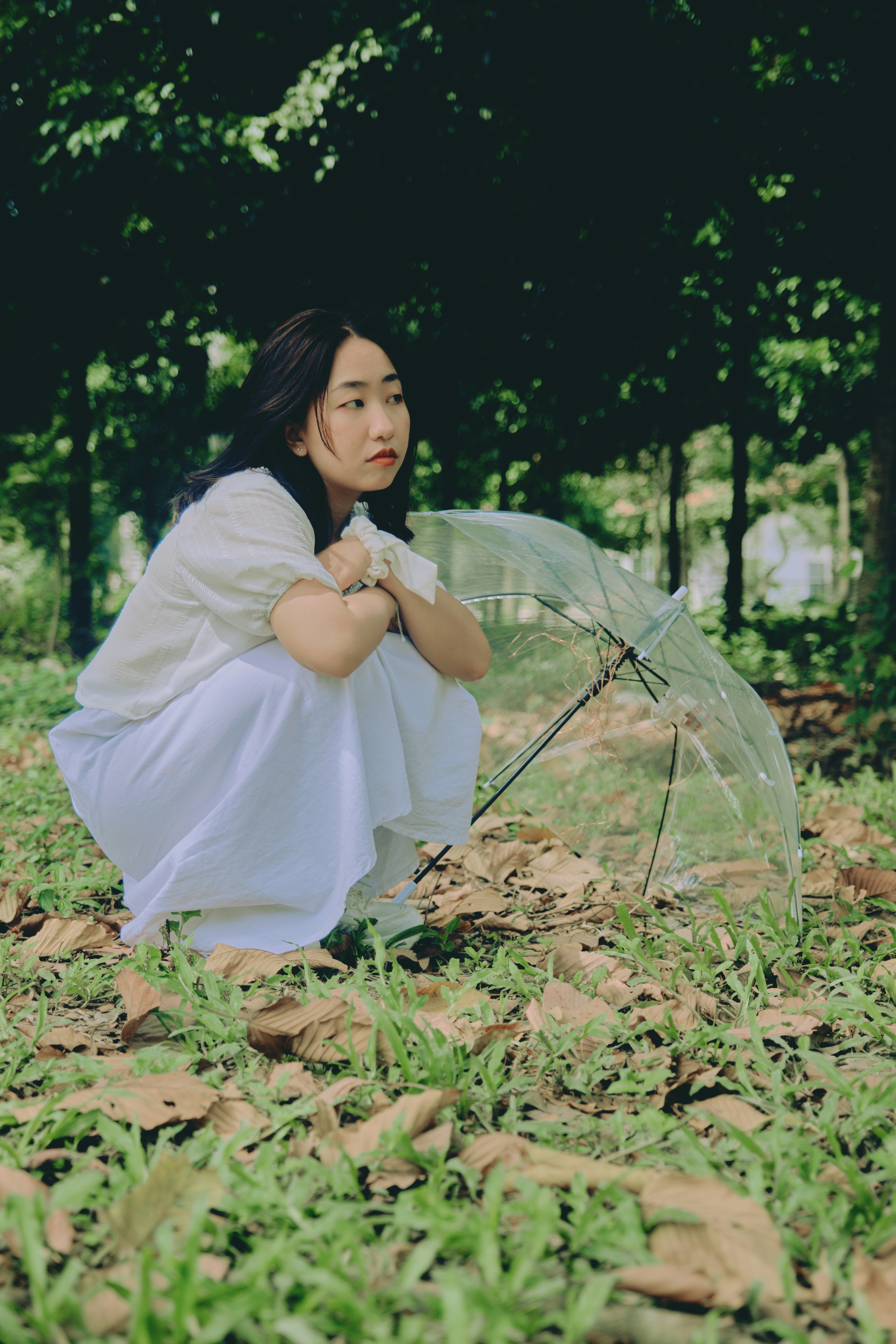 woman in white dress sitting on ground covered with dried leaves