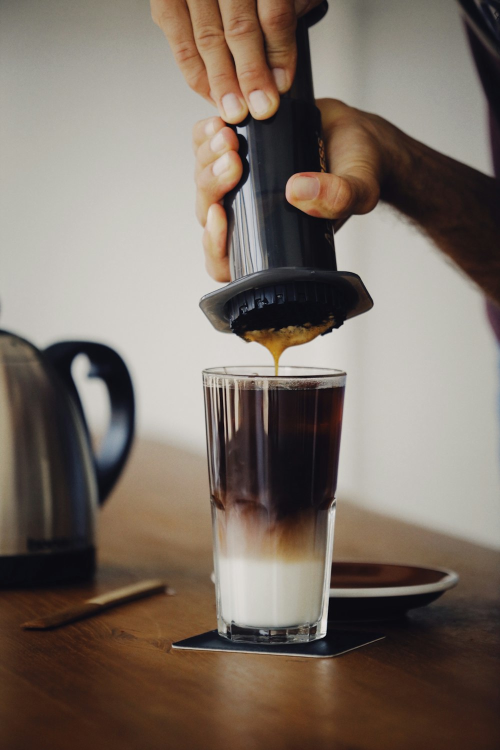 person holding clear drinking glass with brown liquid