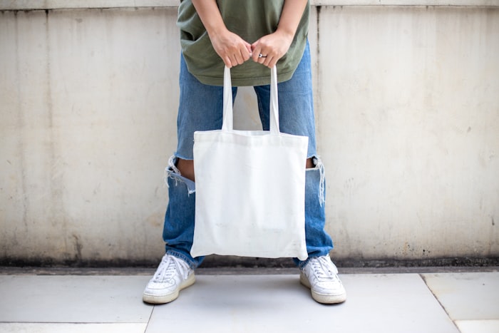 Person holding a reusable white canvas tote bag