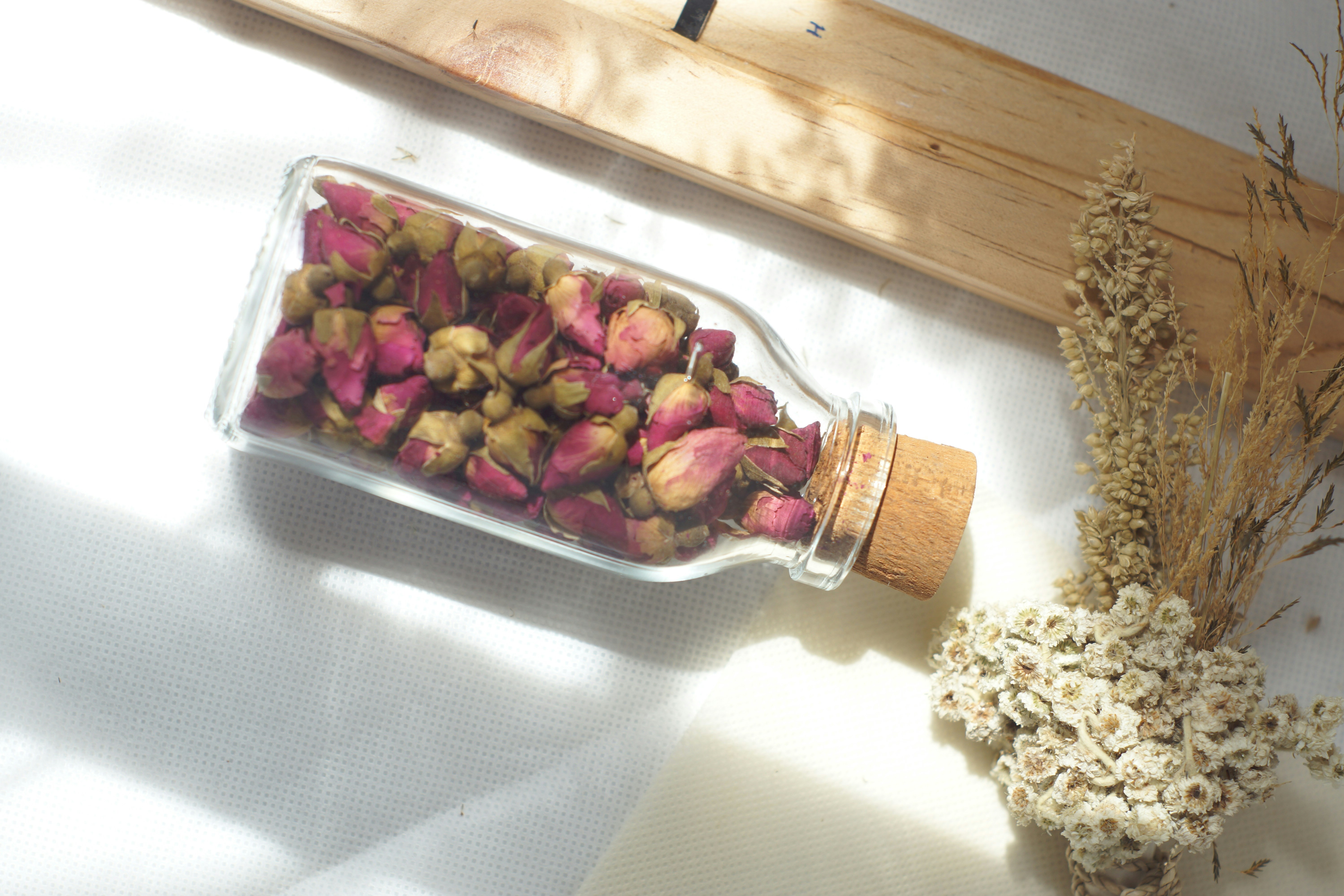 Ahşap bir zemin üzerinde damlalıklı cam şişede acı badem yağı ve yanında taze bademler.