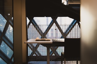 A minimalist office space with a single chair facing a large window overlooking a cityscape.
