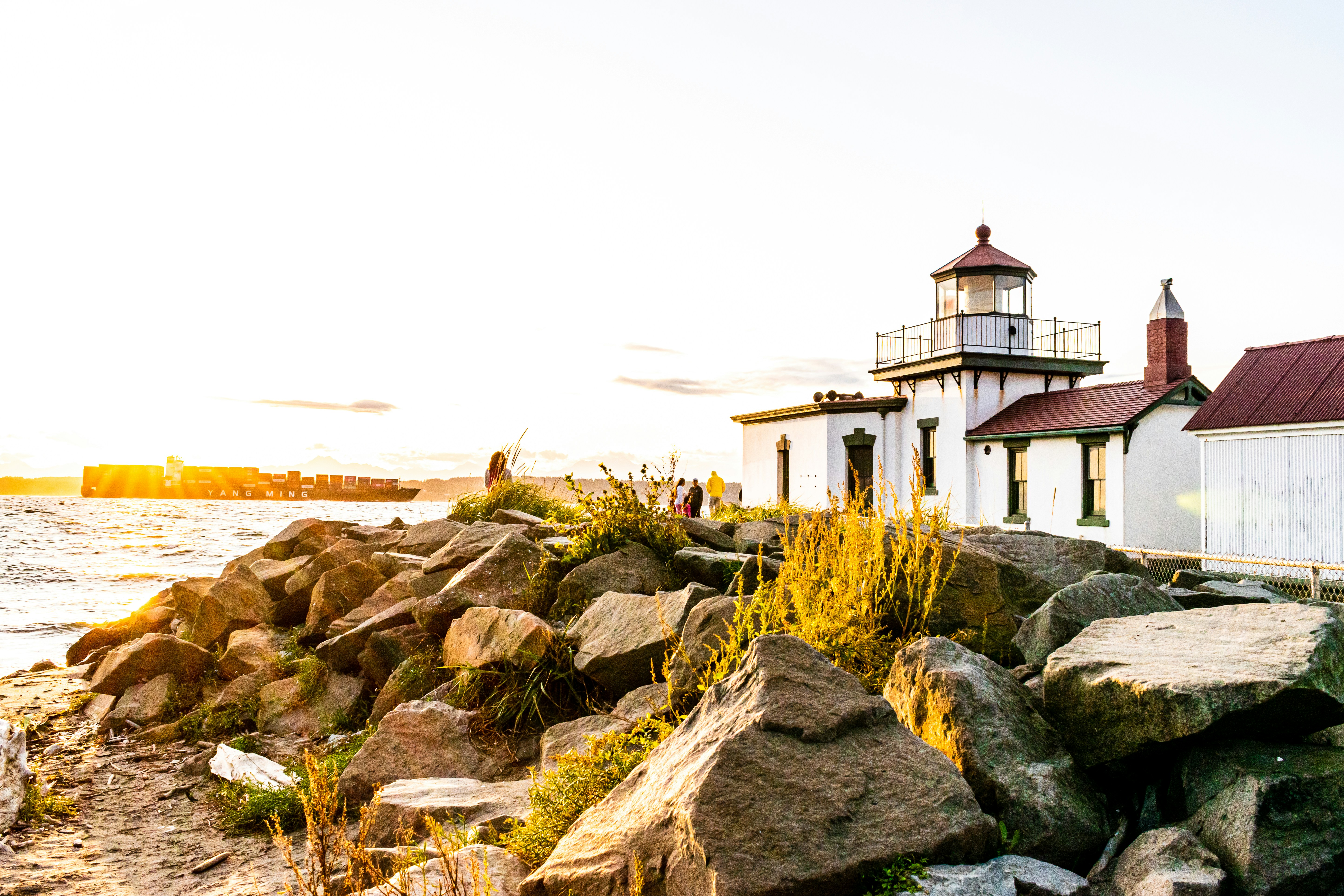 white and red concrete house on rocky shore during daytime