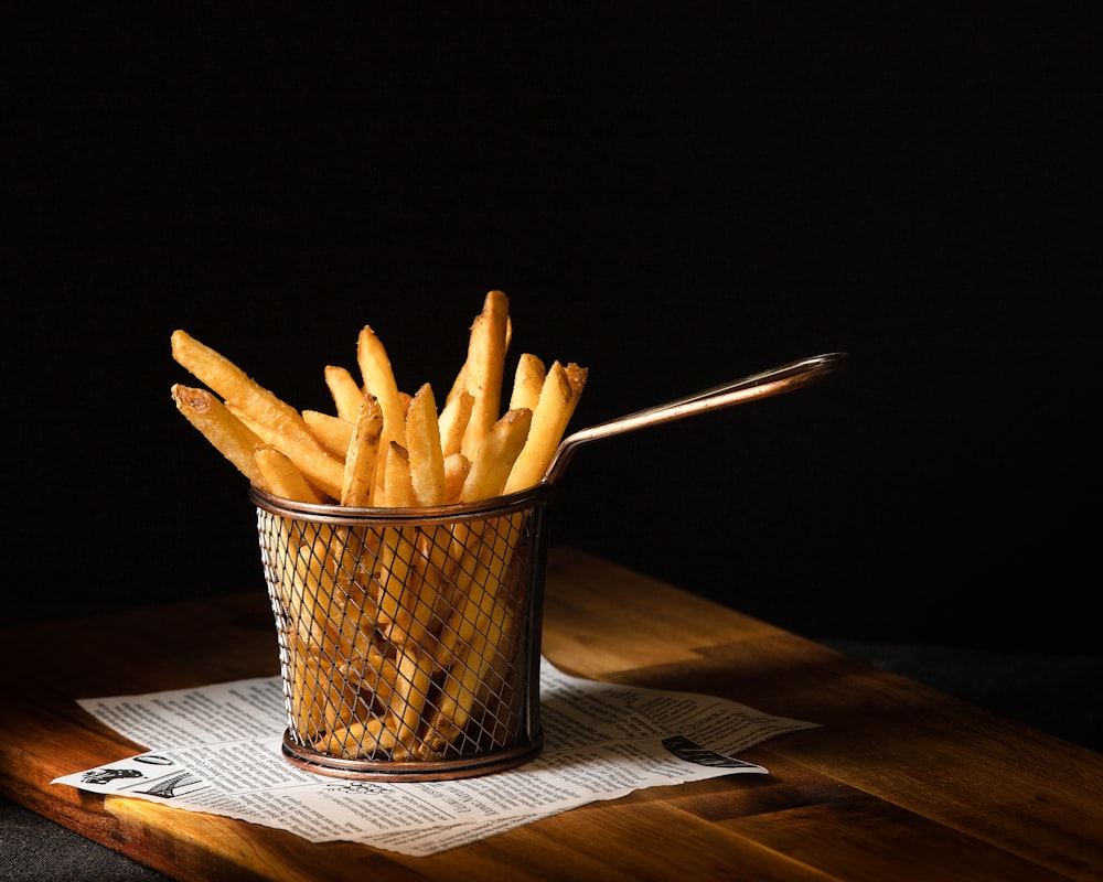 Una canasta de papas fritas sentada encima de una mesa de madera