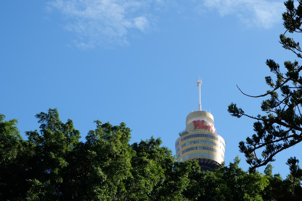 white and red tower near green trees under blue sky during daytime