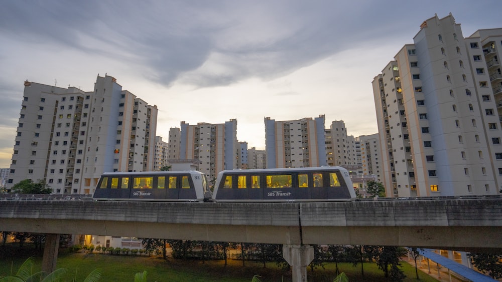 blue and white train on rail near city buildings during daytime