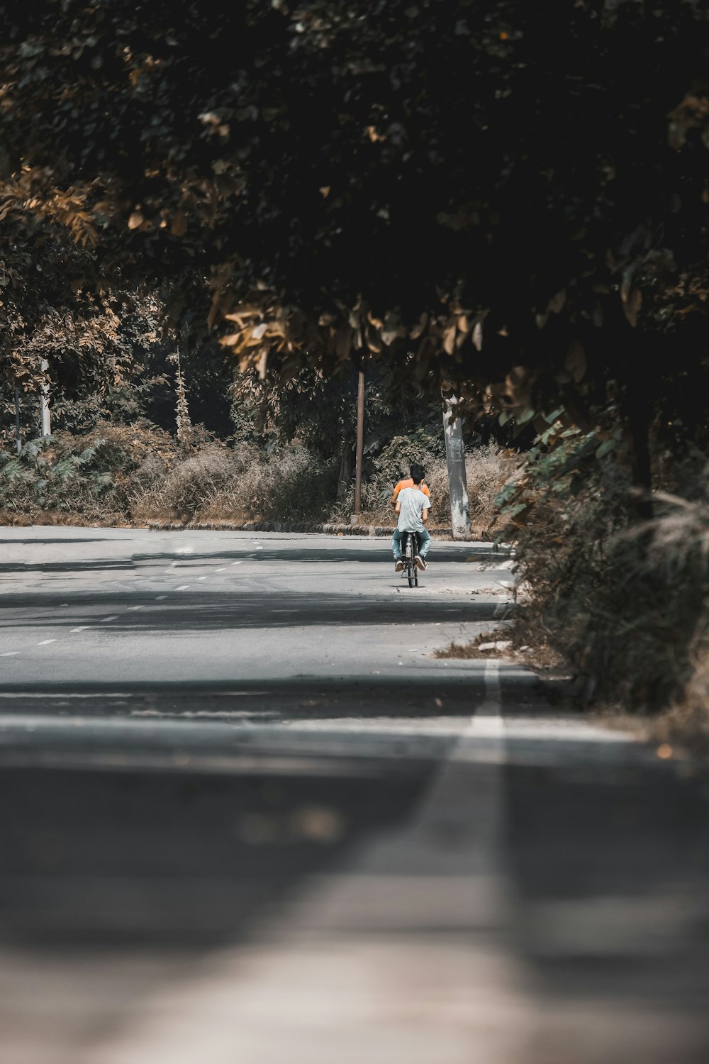 hombre con camisa blanca y jeans azules montando en bicicleta en la carretera durante el día