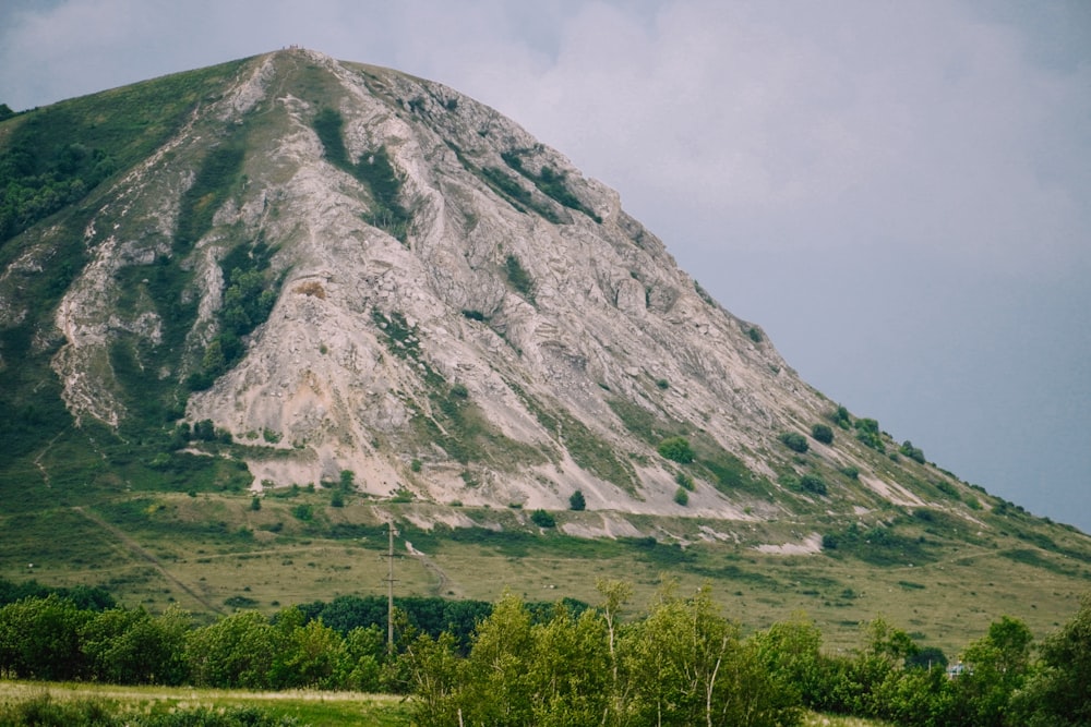 green grass field near mountain under white sky during daytime