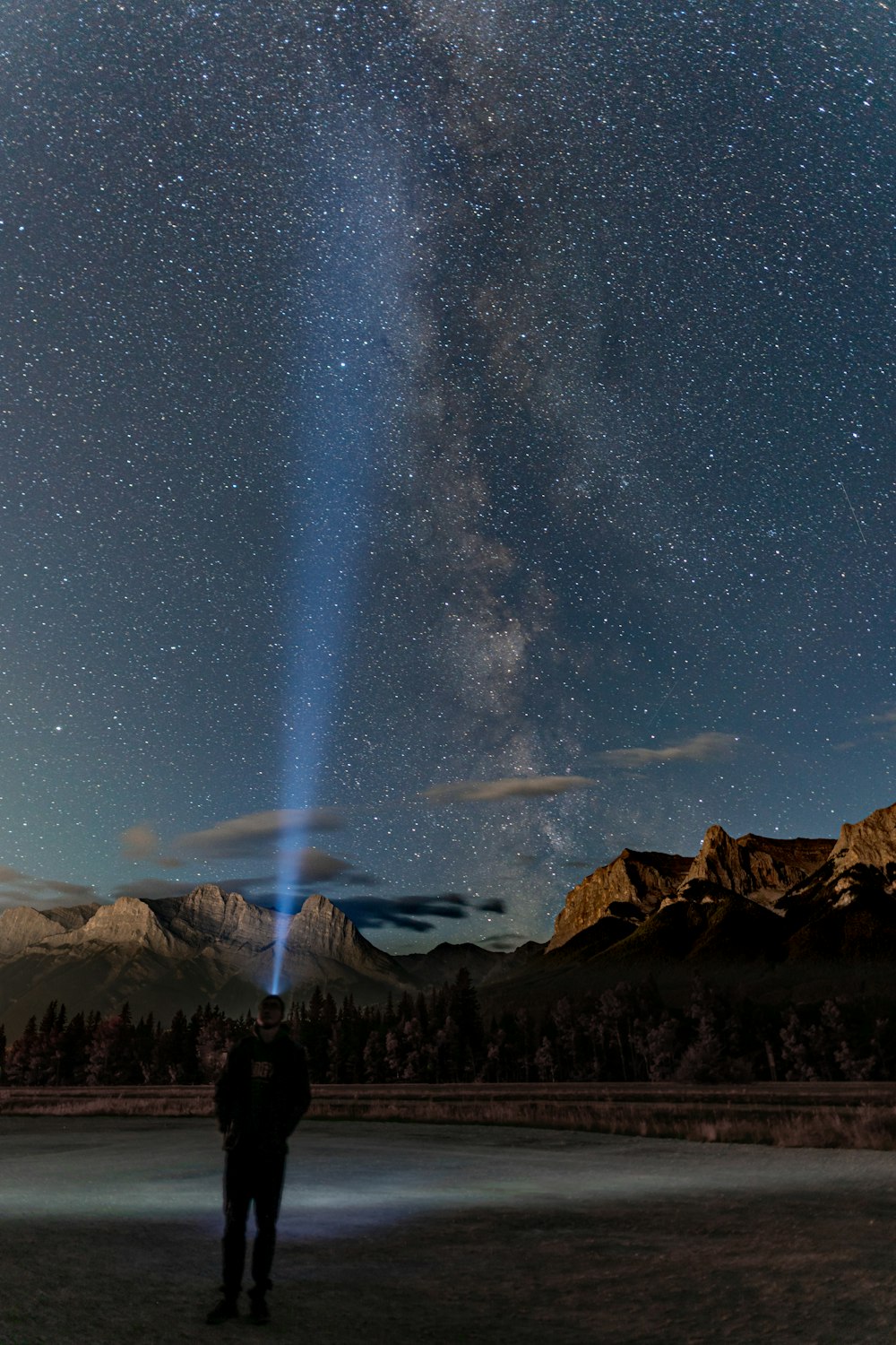 person standing on rock mountain under starry night