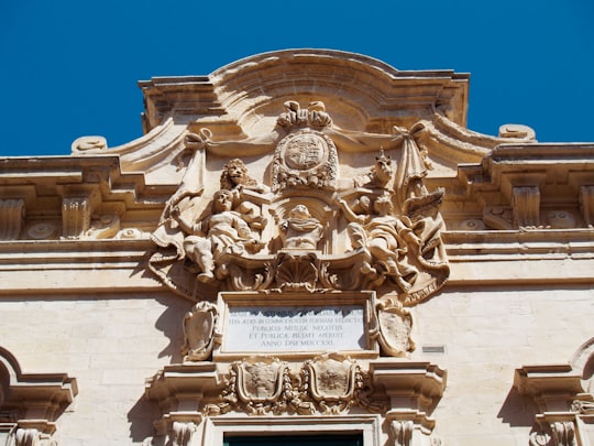 low angle photography of beige concrete building under blue sky during daytime in Valletta Malta